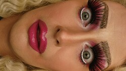 Drag Queen mit dramatischem Make-up, langen Wimpern und überraschtem Gesichtsausdruck