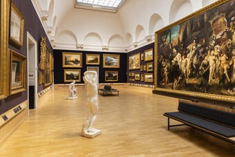 Museumsgalerie mit dunklen Wänden, großformatigen Gemälden und Bänken in der Mitte des Raums