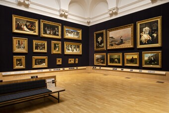 Museumsgalerie mit gerahmten Gemälden an dunklen Wänden und einer Bank in der Mitte