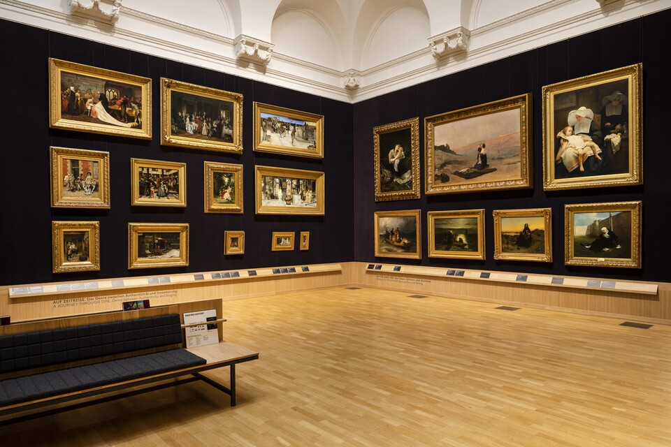 Museumsgalerie mit gerahmten Gemälden an dunklen Wänden und einer Bank in der Mitte