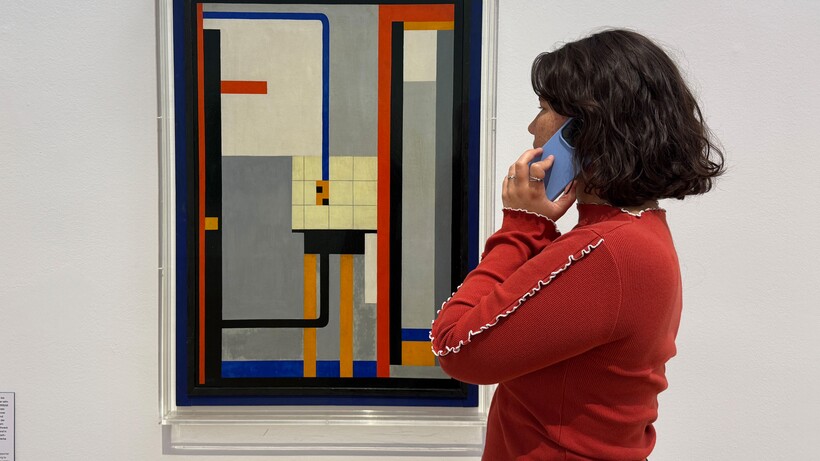Frau in rotem Pullover betrachtet abstraktes Gemälde mit geometrischen Formen in der Ausstellung »This Is the Modern World«