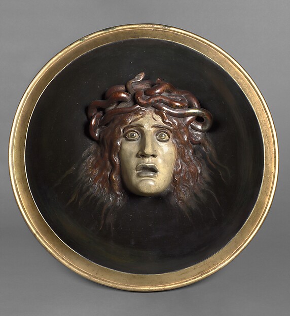 Rundes Medaillon mit Medusa-Kopf aus Bronze auf dunklem Hintergrund mit goldenem Rahmen