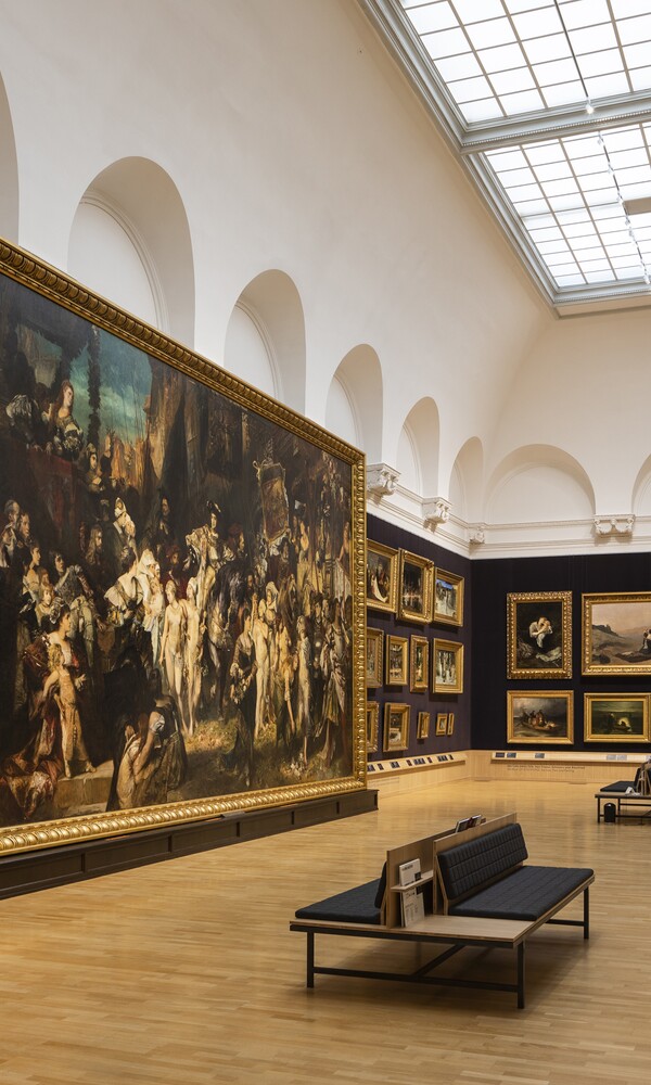 Großer Museumsraum mit dunklen Wänden, historischen Gemälden, Sitzbänken und Oberlicht